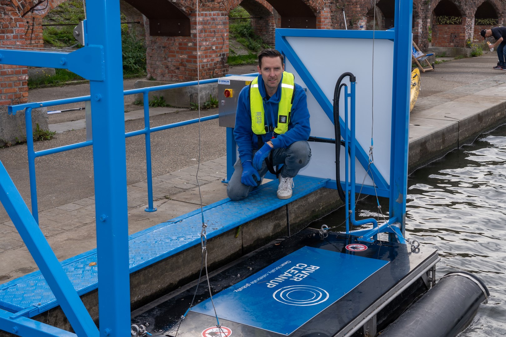 Thomas De Groote of River Cleanup posing with the River Skimmer in Ghent, a machine designed by Construct Masters.